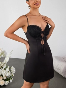 Détail de dentelle sur robe courte en satin noir avec découpe frontale et nœud ruban