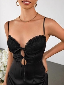 Détail de robe en satin noir avec dentelle florale et design creux à lacets