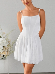 Close-up of white corset lace dress featuring delicate floral mesh and pleated skirt detail