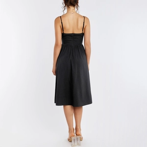 Elegant black backless midi dress with spaghetti straps and flared hem in studio setting