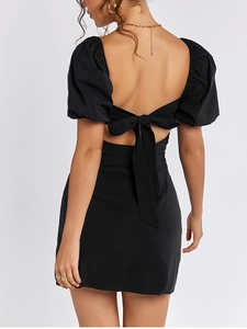 Detail of backless black mini dress featuring a delicate bow tie and puff sleeves