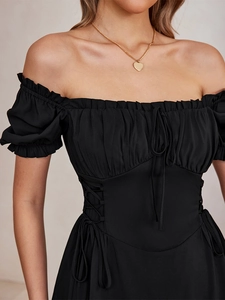 Close-up of black puff sleeve mini dress with lace-up waist detail and ribbon bow