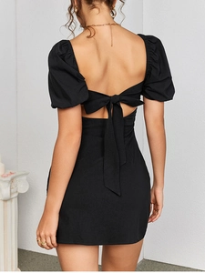 Detail of a black open-back dress featuring a stylish bow tie and puffy lantern sleeves