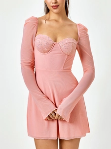 Dettaglio dell'abito in rete rosa con corpetto in pizzo con paillettes e maniche lunghe