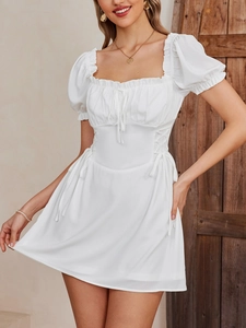 Detail of white puff sleeve mini dress featuring ruffled square neck and lace-up waist detail