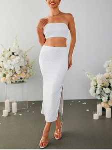 Dettaglio di un completo bianco a due pezzi in pizzo con top a fascia e gonna a spacco