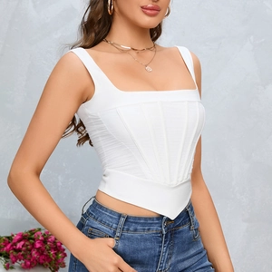 White corset top with square neck and V-hem paired with jeans against a grey wall
