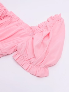 Detail of pink bubble sleeve neckline with delicate ruffled edges and soft fabric texture