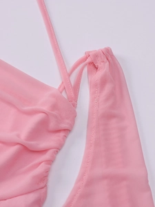 Détail de tissu en maille rose avec bretelles fines et textures de coutures plissées