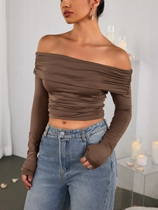 Close-up of brown ruched off-shoulder cropped long sleeve top with soft fabric texture