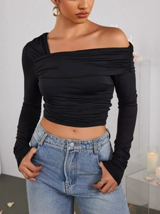 Détail du haut noir asymétrique à manches longues avec élégant plissage latéral