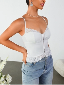 Détail d'un haut corset blanc avec bordure en dentelle brodée et fermeture à agrafes devant