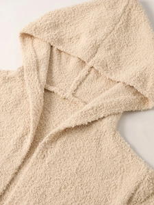 Close-up of soft cream knit fabric texture on a cozy hooded winter cardigan jacket