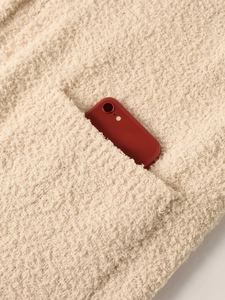Detailed close-up of a beige fleece coat pocket with a red phone showing functionality