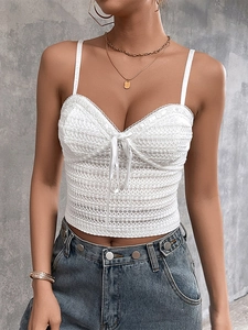 Detailed view of white lace camisole with bow tie and geometric crochet texture