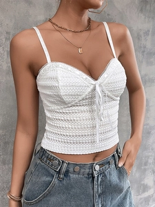 Close-up of white knitted camisole featuring delicate lace trim and front bow detail