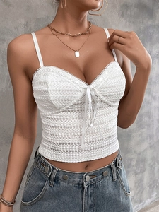 Detailed shot of white lace crop top with bow tie and intricate scalloped knit texture