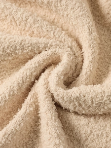 Close-up macro of warm beige sherpa fleece texture on a hooded winter knitted coat