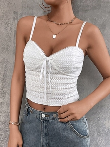 Detail of white lace bustier top featuring thin straps and a front bow knot detail
