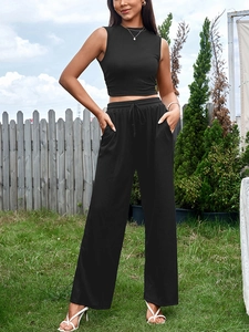 Détail d'un crop top noir sans manches et d'un pantalon large à taille haute avec cordon