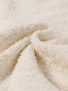 Gros plan sur un tissu tricoté en peluche blanche montrant la texture épaisse et douce