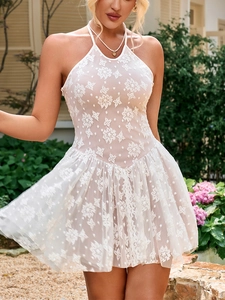 Detail of white lace halter dress showing floral embroidery and pleated A-line skirt