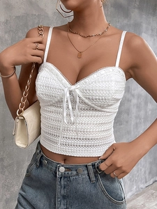 Close-up of white lace camisole featuring delicate bow tie and intricate crochet texture