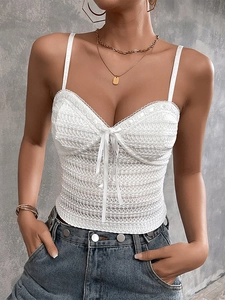 Detail of white lace camisole featuring intricate crochet embroidery and a tie-up bow