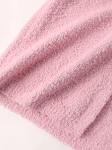 Close-up of soft pink knitted plush fabric showing fluffy texture on hooded cardigan
