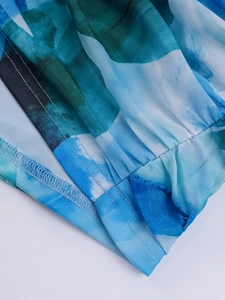 Close-up of mesh fabric with blue and green floral print and overlock stitching detail