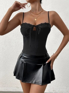 Close-up of black tank top with lace trim, bow tie details, and textured leather skirt