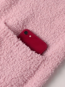 Detail of pink fleece hoodie showing a deep functional pocket with a mobile phone
