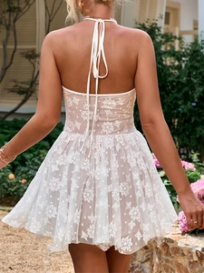 Back view of a cream lace halter dress featuring an open back and delicate floral embroidery