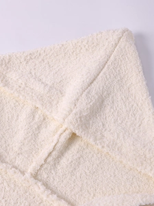 Detailed close-up of soft cream faux fur fabric with high-quality stitching on knit coat
