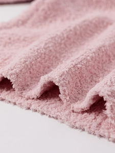 Détail de la texture d'un ensemble en maille rose douce avec aspect fausse fourrure