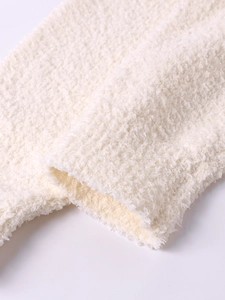 Close-up of soft cream knit fabric and cuff texture on a hooded winter cardigan