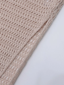 Dettaglio ravvicinato del tessuto beige a maglia con trama traforata e cuciture