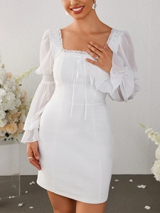Détail de l'encolure carrée avec dentelle et nœud en ruban sur la robe blanche en mousseline