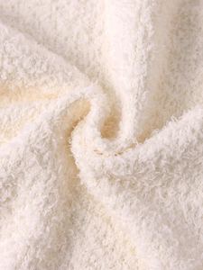 Macro shot of soft cream faux shearling fabric texture on a winter hooded knit jacket