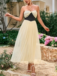 Detalle de vestido elegante de malla con corpiño plisado crema y banda negra de talle alto