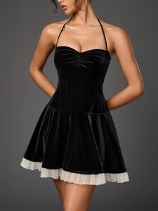 Détail de robe noire en velours avec licou, plis et bordure en dentelle blanche au bas