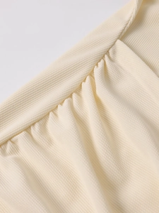 Detailed close-up of cream white knitted fabric with elegant pleated texture and stitching