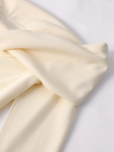 Close-up detail of cream white ribbed knit fabric texture and high-quality stitching seams