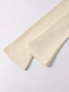 Macro detail of cream waffle knit fabric showing soft texture and ribbed cuffs