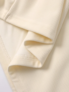 Detailed macro view of cream waffle knit fabric texture and fine stitching quality