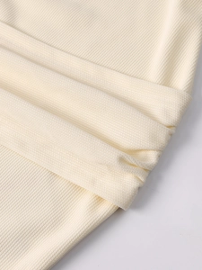 Close-up of off-white ribbed knit fabric texture with elegant draped folds