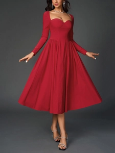 Détail d'une robe trapèze rouge avec décolleté en cœur élégant et longues manches plissées