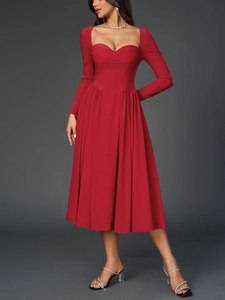Détail de robe rouge à manches longues avec décolleté cœur et jupe plissée en ligne A