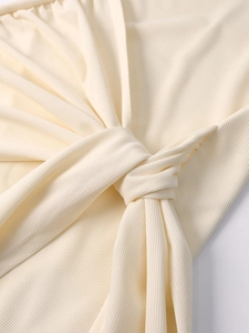 Detail shot of the twist knot design and textured knit fabric on an off-white mini dress