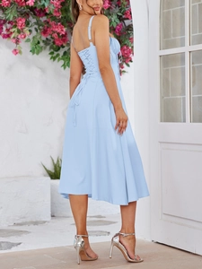 Detail of light blue midi dress showing crisscross back straps and ruched fabric texture